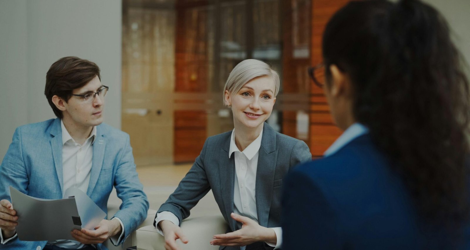 Drei Geschäftsleute diskutieren gemeinsam Dokumente während eines Meetings in einem modernen Büro.