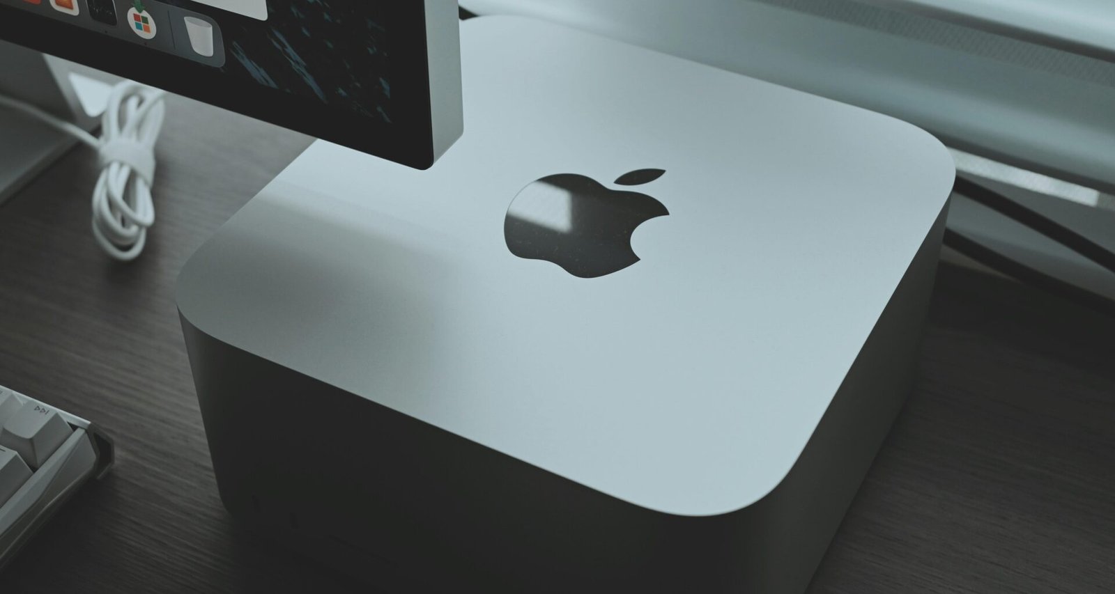 Apple Computer steht auf einem Holzschreibtisch in moderner Büroumgebung mit hellem Tageslicht.
