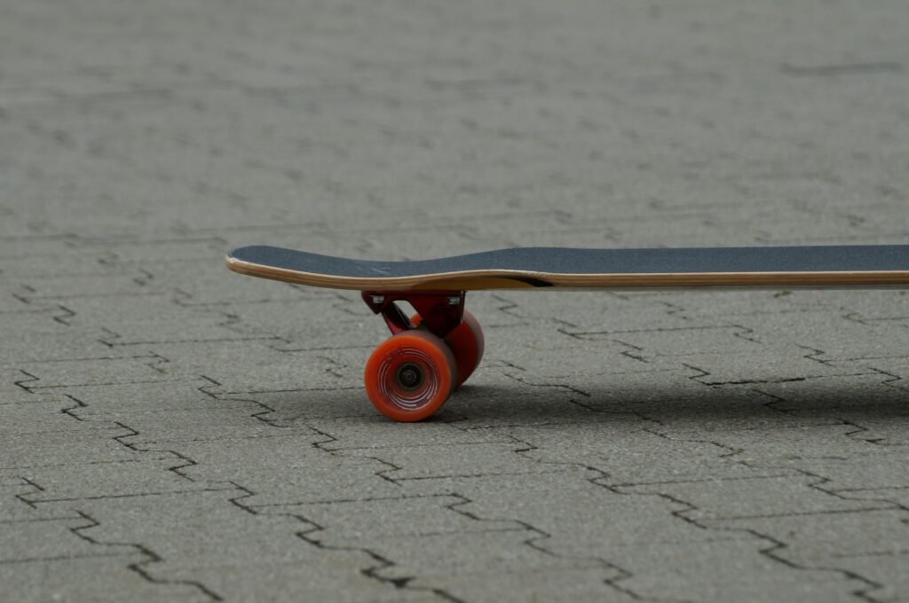 Ein Skateboard mit einer roten Rolle steht auf dem Boden, ideal zur Illustration von Themen über Skateboarding und urbane Trends.