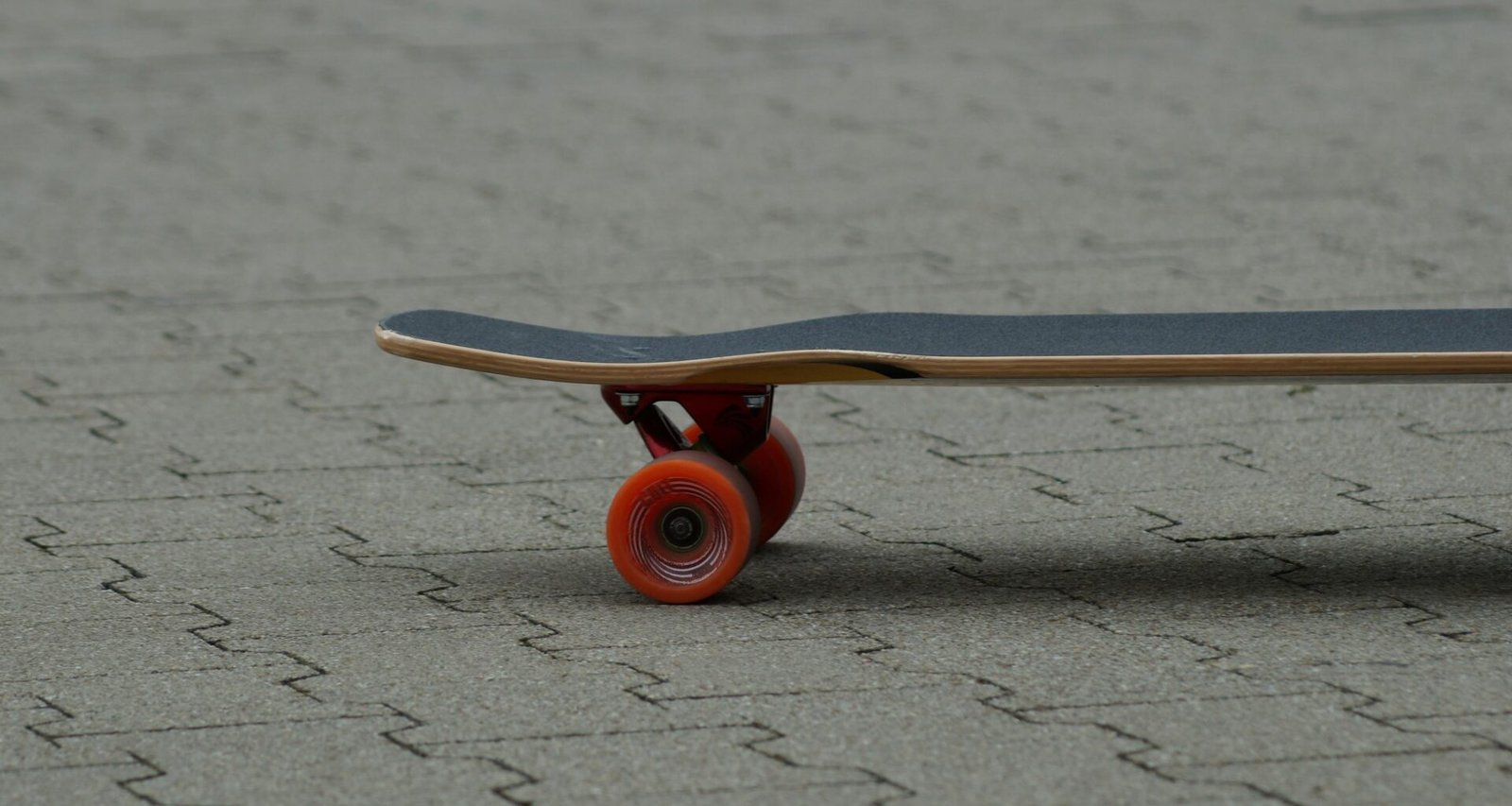 Ein Skateboard mit rotem Rad steht auf dem Boden, aufgenommen für einen Artikel über urbane Trends und Mobilität im Alltag.