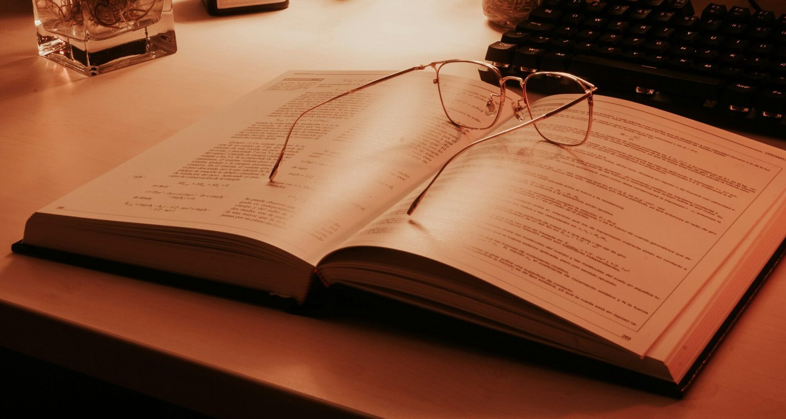Ein offenes Buch mit einer klassischen Brille darauf, liegend auf einem Tisch, Symbol für Lernen und Wissen.