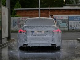 Ein parkendes Auto ist mit einer dicken Schicht aus Eis und Wasser bedeckt, was winterliche Wetterbedingungen zeigt.