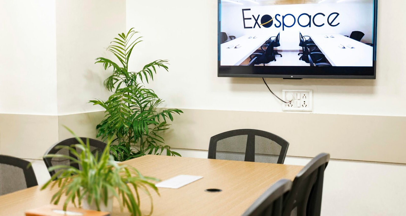 Besprechungsraum mit modernem Design, auf dessen Bildschirm das Exospace Logo zu sehen ist