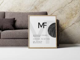 Ein leerer Bilderrahmen lehnt an einer Wand direkt neben einem gemütlichen Sofa auf einem Holzboden.