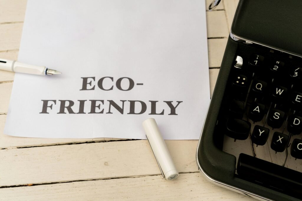 Papier mit der Aufschrift eco-friendly neben einer Schreibmaschine auf einem Holztisch, Symbol für nachhaltige Büroarbeit