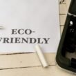 Papier mit der Aufschrift eco-friendly neben einer Schreibmaschine auf einem Holztisch, Symbol für nachhaltige Büroarbeit