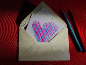 Ein Stück weißes Papier, auf dem mit schwarzer Linie ein Herz gezeichnet wurde, liegt auf einem hellen Untergrund.