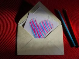 Ein weißes Stück Papier mit einem schwarzem Herz darauf, flach auf eine helle Oberfläche gelegt