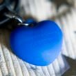 Blauer herzförmiger Anhänger an einem silbernen Schlüsselring auf weißem Hintergrund