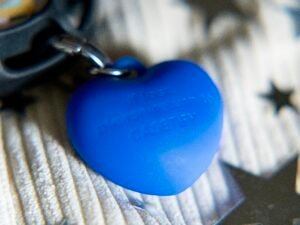 Blauer herzförmiger Anhänger an einem silbernen Schlüsselring auf weißem Hintergrund