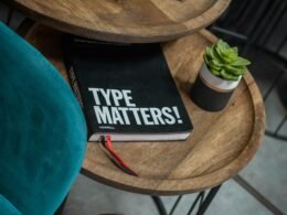 Ein geschlossenes Buch ruht auf einem hölzernen Tisch und stellt eine ruhige Lese- oder Arbeitsumgebung dar.