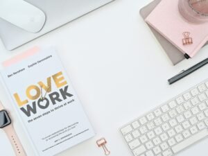 Ein Buch liegt auf einem Schreibtisch neben einer Computertastatur – ideal für produktives Arbeiten im Büroalltag.