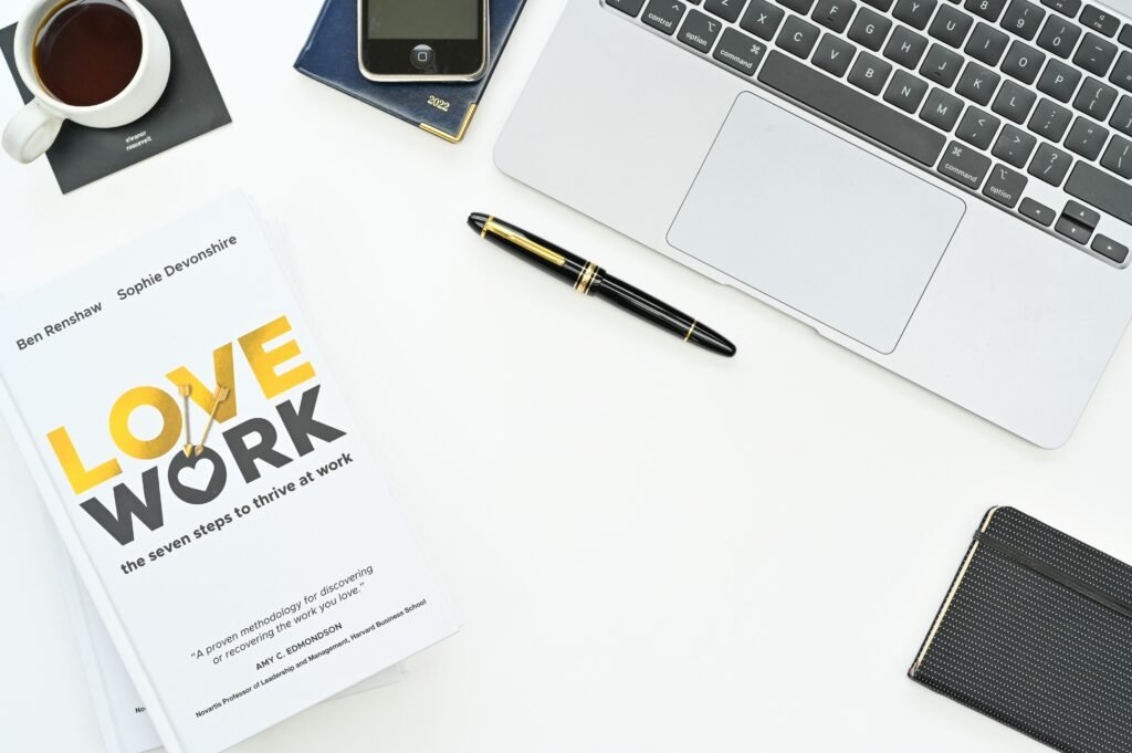 Ein aufgeschlagenes Buch neben einem Laptop auf einem Holztisch – ideale Kombination für effektives Arbeiten und digitales Lernen.