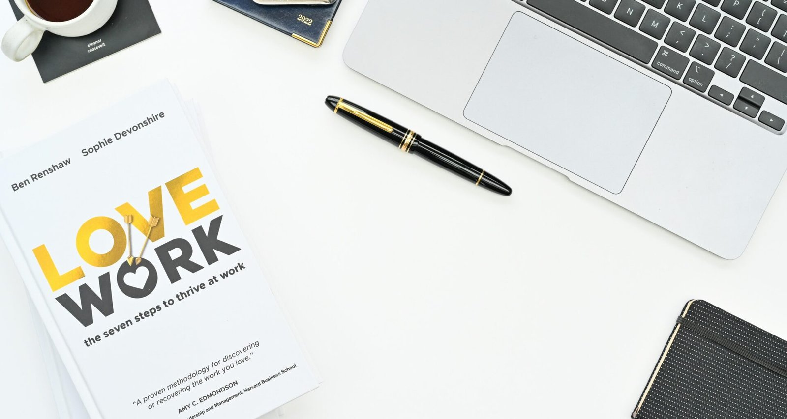 Ein aufgeschlagenes Buch neben einem Laptop auf einem Holztisch – ideale Kombination für effektives Arbeiten und digitales Lernen.