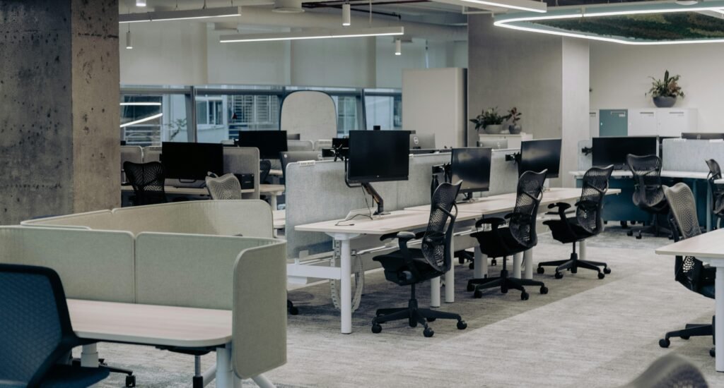 Großraumbüro mit vielen Schreibtischen und Stühlen, eingerichtet für gemeinsames Arbeiten in einer modernen Arbeitswelt
