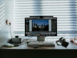 Computerarbeitsplatz mit Monitor, auf dem eine Stadtsilhouette zu sehen ist, auf einem Schreibtisch in moderner Umgebung