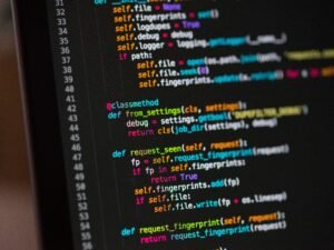 Computerbildschirm mit offenem Quellcode, zahlreiche Programmierzeilen, dunkle Benutzeroberfläche, Fokus auf Entwicklung