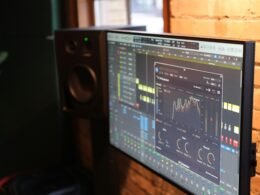 Ein Computerbildschirm steht auf einem Schreibtisch direkt neben einer roten Backsteinwand in einem modernen Raum.