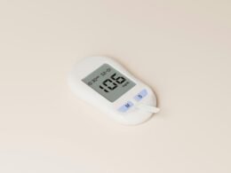 Ein digitales Thermometer liegt auf einer weißen Oberfläche und zeigt eine aktuelle Temperaturanzeige.