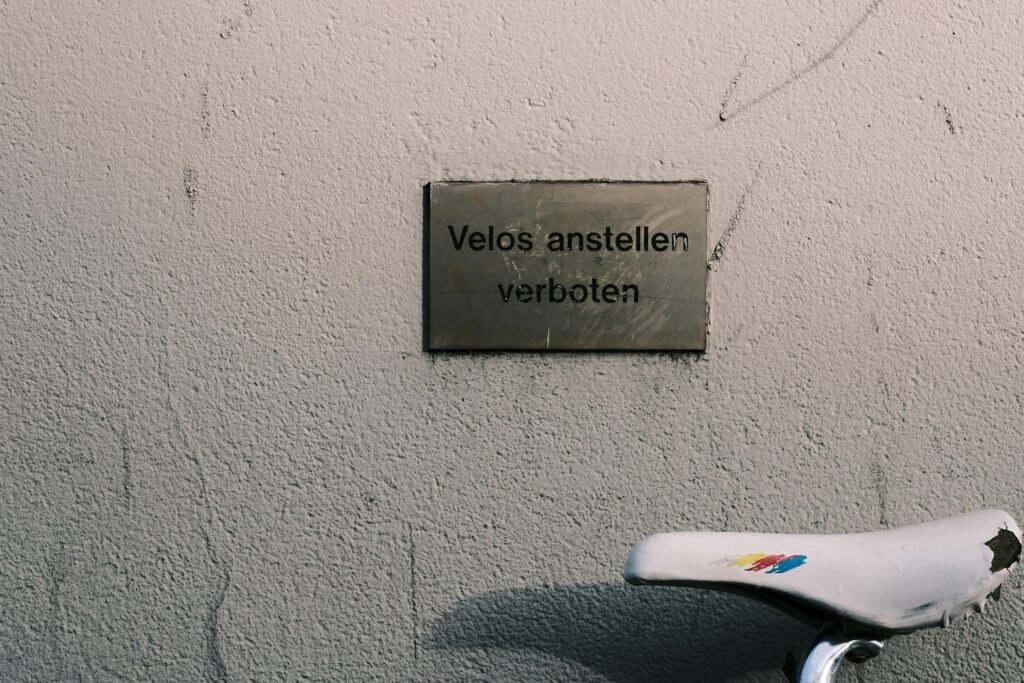 Fahrrad steht neben einer Mauer mit gut sichtbarem Schild, aufgenommen in einem städtischen Umfeld