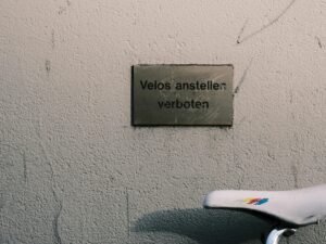 Fahrrad steht neben einer Mauer mit gut sichtbarem Schild, aufgenommen in einem städtischen Umfeld