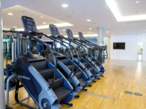 Ein gym mit verschiedenen Trainingsgeräten, Hanteln und Laufbändern in einem modernen, gut beleuchteten Raum