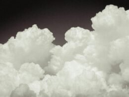 Ein Flugzeug fliegt durch einen Himmel, der mit dichten Wolken bedeckt ist, aufgenommen in luftiger Höhe.