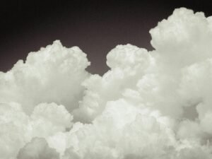 Ein Flugzeug fliegt durch einen Himmel, der mit dichten Wolken bedeckt ist, aufgenommen in luftiger Höhe.