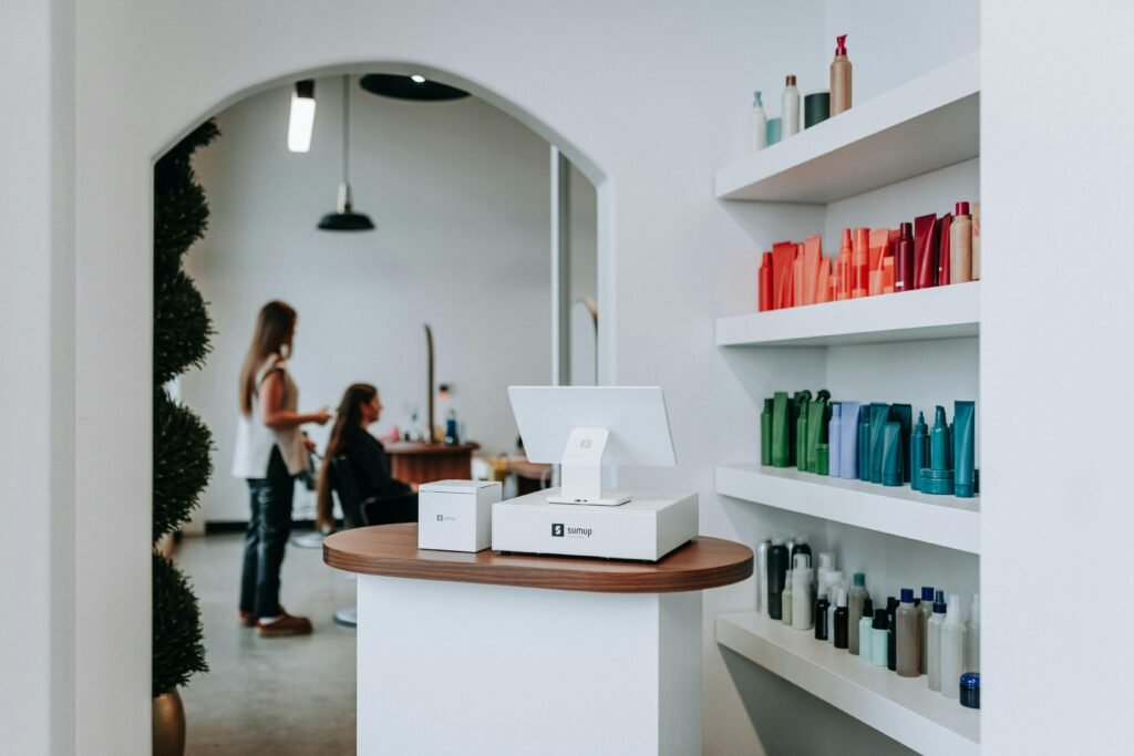 Innenraum eines Friseursalons mit Regalen voller Haarprodukte und mehreren Kunden beim Friseurservice.