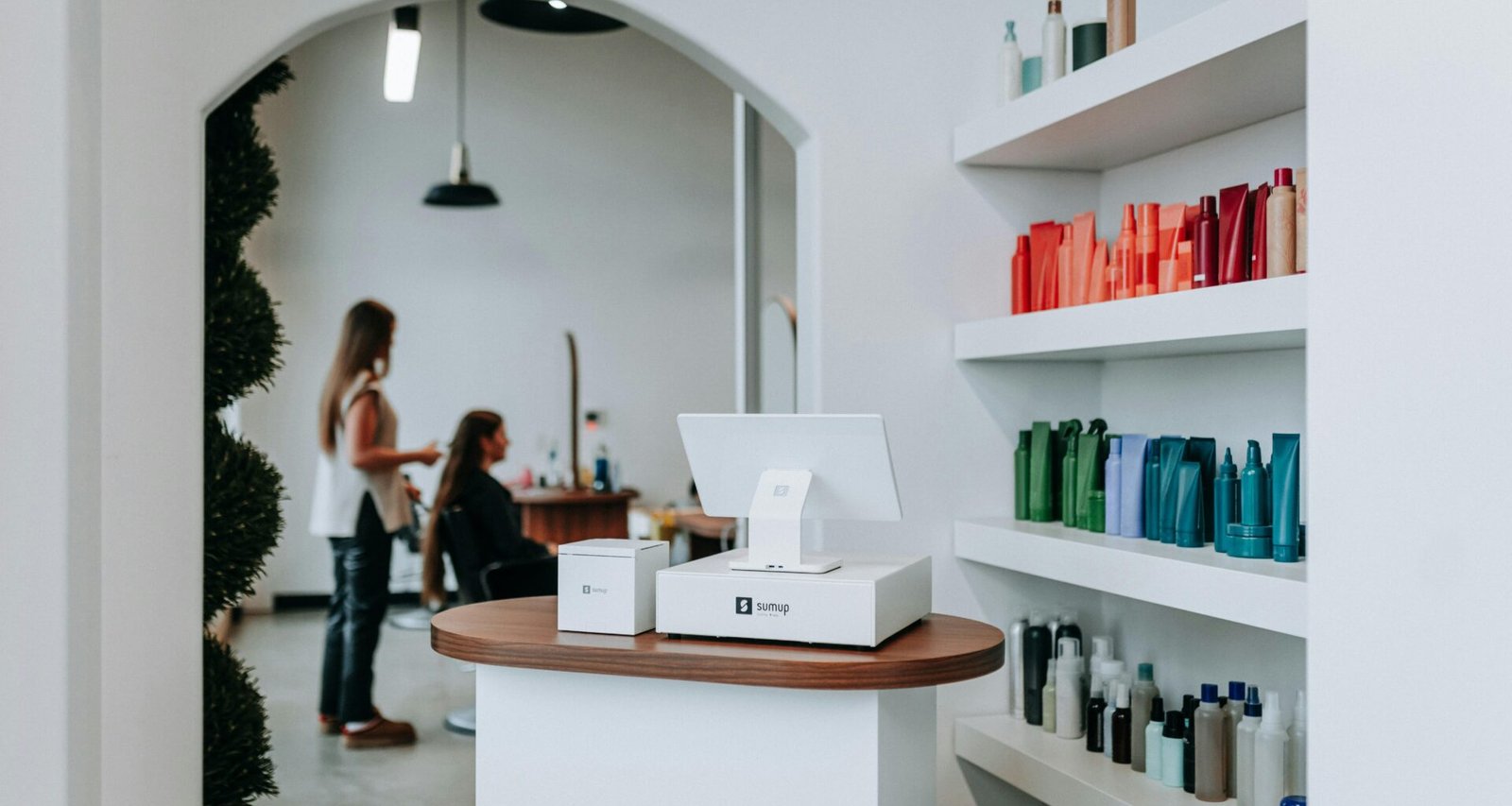 Innenraum eines Friseursalons mit Regalen voller Haarprodukte und mehreren Kunden beim Friseurservice.