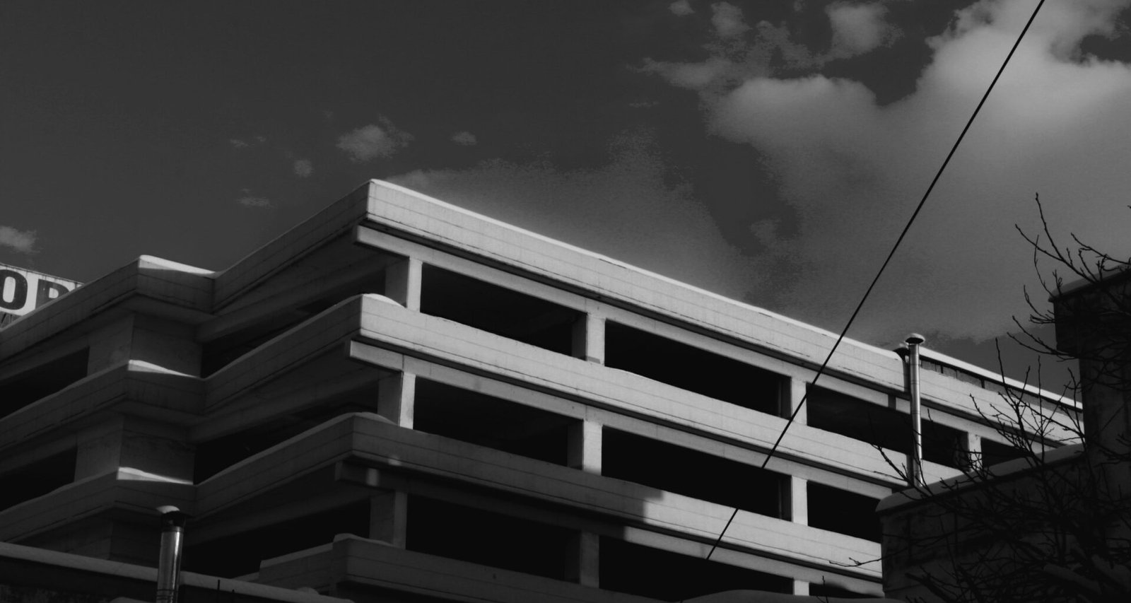 Ein modernes Gebäude vor einem bewölkten Himmel, aufgenommen aus Bodensicht; der Fokus liegt auf Architektur und Struktur.