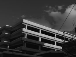 Ein modernes Gebäude vor einem bewölkten Himmel, aufgenommen aus Bodensicht; der Fokus liegt auf Architektur und Struktur.