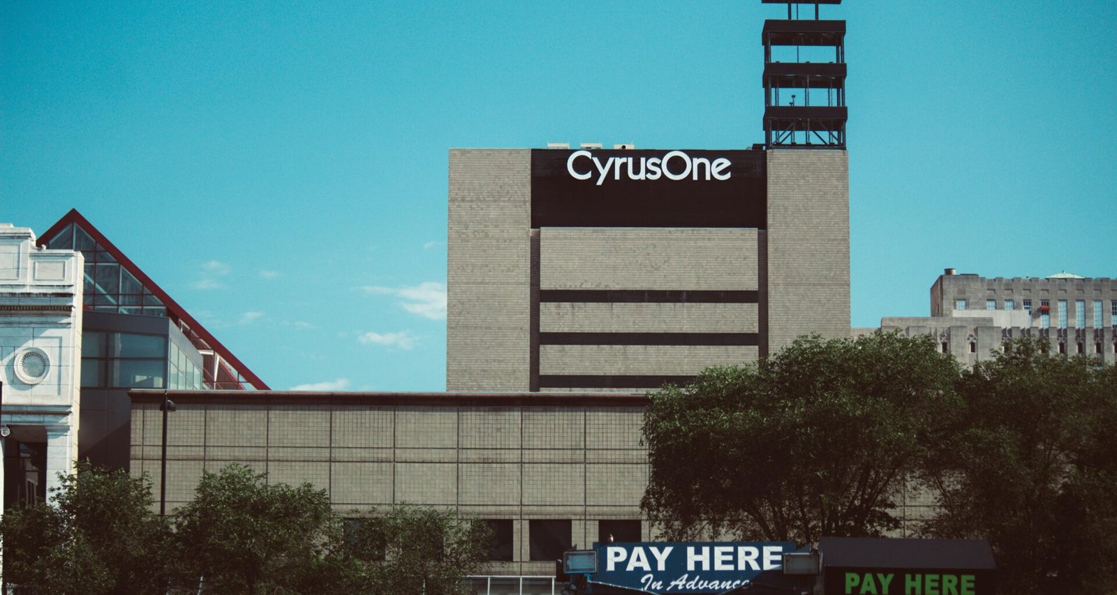 Modernes Gebäude mit großer "Pay Here"-Beschilderung auf dem Dach, Sinnbild für digitale Zahlungsoptionen in Städten