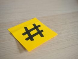 Gelbes Stück Papier mit darauf gezeichnetem Hashtag-Zeichen, fotografiert als Symbol für Online-Kommunikation