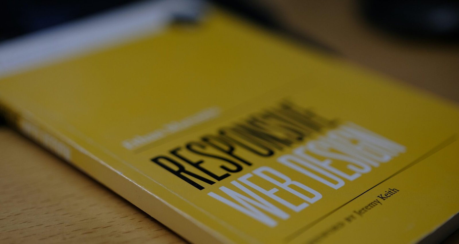 Gelbes Buch liegt auf einem hölzernen Tisch, Darstellung von Wissen und Kreativität im Arbeitsumfeld