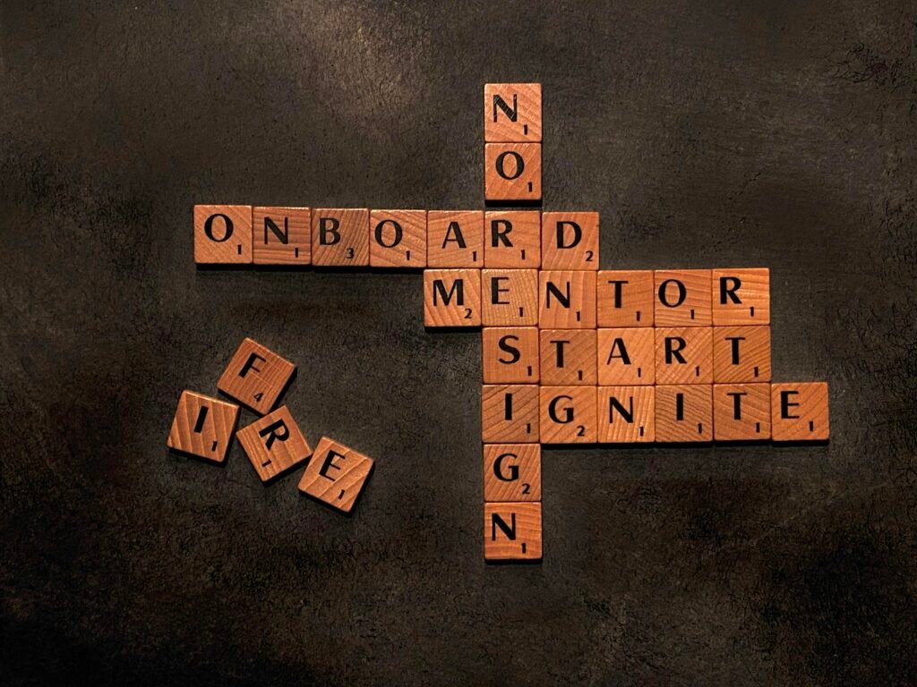 Auf einem Scrabble-Brett liegen die Wörter Mentor, Start und Nein aus Buchstabensteinen nebeneinander.