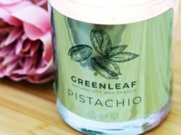 Ein transparenter Glasbehälter mit einem grünen Plastikdeckel steht auf einer neutralen Oberfläche und ist leer.