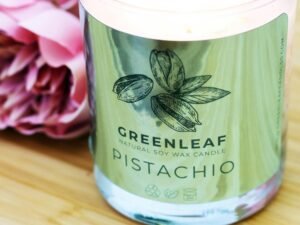 Ein transparenter Glasbehälter mit einem grünen Plastikdeckel steht auf einer neutralen Oberfläche und ist leer.