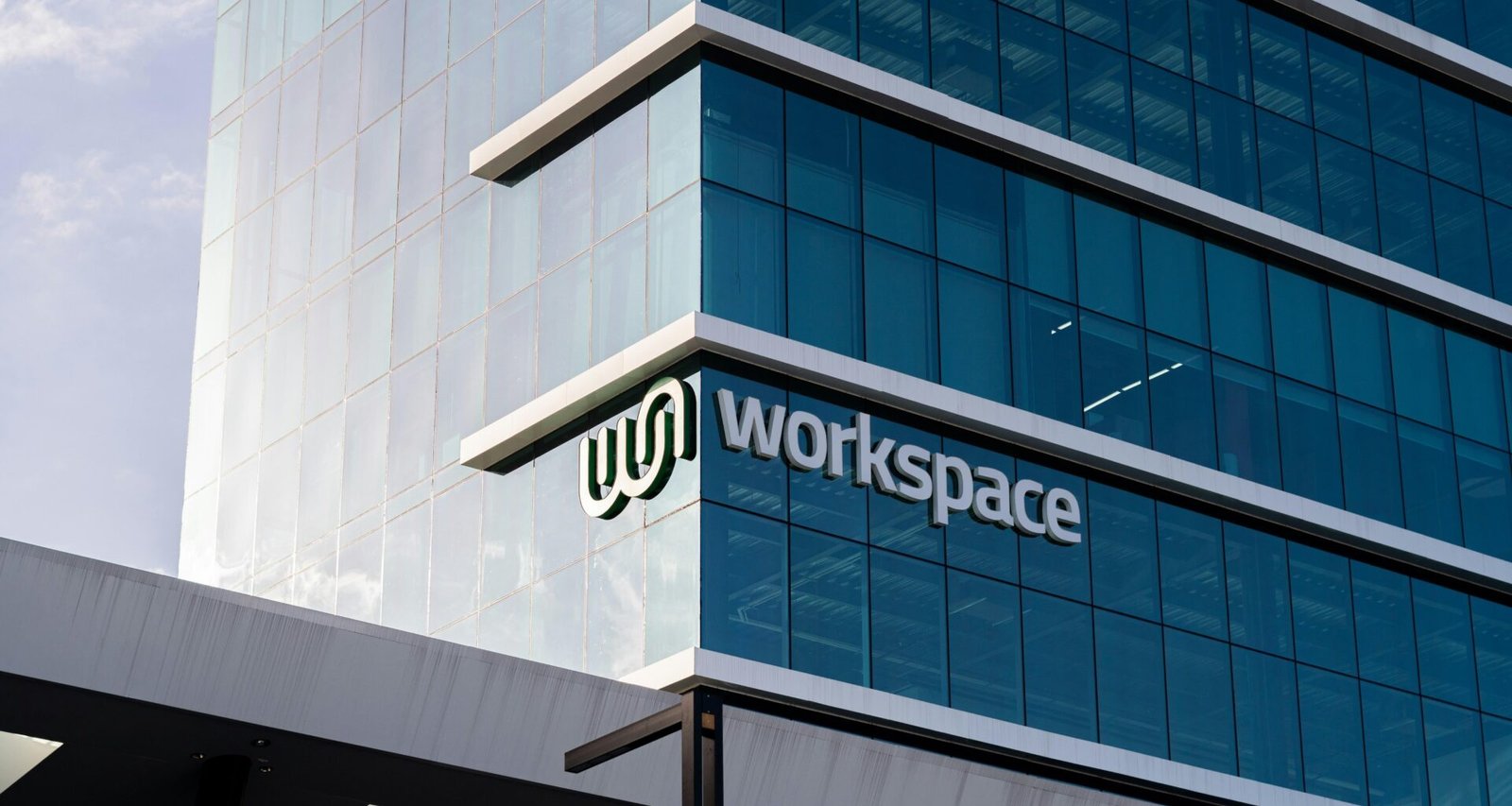 Großes, modernes Bürogebäude aus Glas mit dem Wort Workspace auf der Fassade, Beispiel für zeitgemäße Architektur.