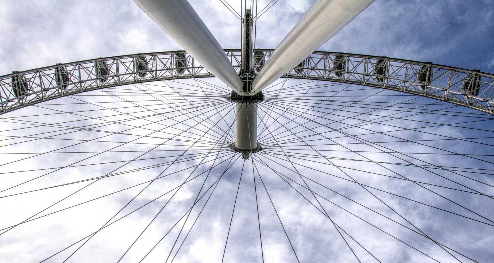 Großes Riesenrad mit mehreren Gondeln vor einem weiten blauen Himmel, Fokus auf Technik und Struktur.