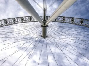 Großes Riesenrad mit mehreren Gondeln vor einem weiten blauen Himmel, Fokus auf Technik und Struktur.
