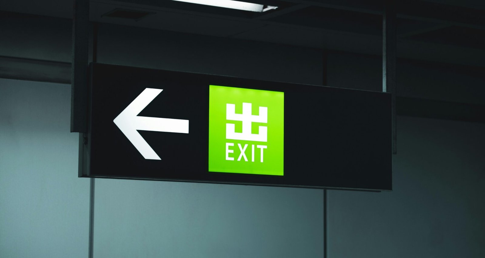 Grünes Notausgangsschild hängt von der Decke und kennzeichnet den Fluchtweg in einem öffentlichen Gebäude