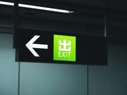 Grünes Notausgangsschild hängt von der Decke und kennzeichnet den Fluchtweg in einem öffentlichen Gebäude