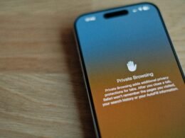 Ein Smartphone liegt auf einem hölzernen Tisch, beleuchtet von Tageslicht, mit Fokus auf technische Details des Geräts.