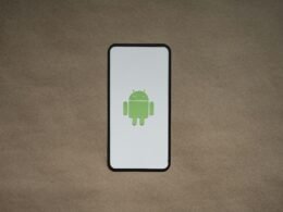 Smartphone mit grünem Symbol auf dem Bildschirm, fotografiert auf einer klaren Oberfläche als Symbol für Techniknutzung