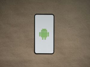 Smartphone mit grünem Symbol auf dem Bildschirm, fotografiert auf einer klaren Oberfläche als Symbol für Techniknutzung