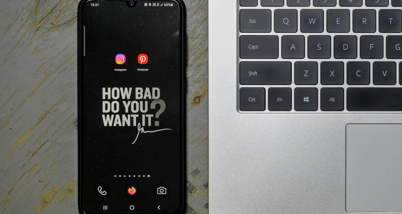 Ein Mobiltelefon liegt neben einem aufgeklappten Laptop auf einem Schreibtisch, beide Geräte sind einsatzbereit.