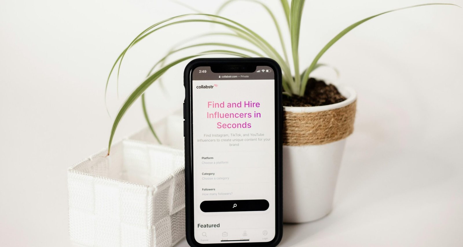 Ein Handy liegt neben einem Blumentopf mit kleiner Pflanze auf einem Tisch, ideal für Themen wie Digitalisierung und Alltagstechnik.