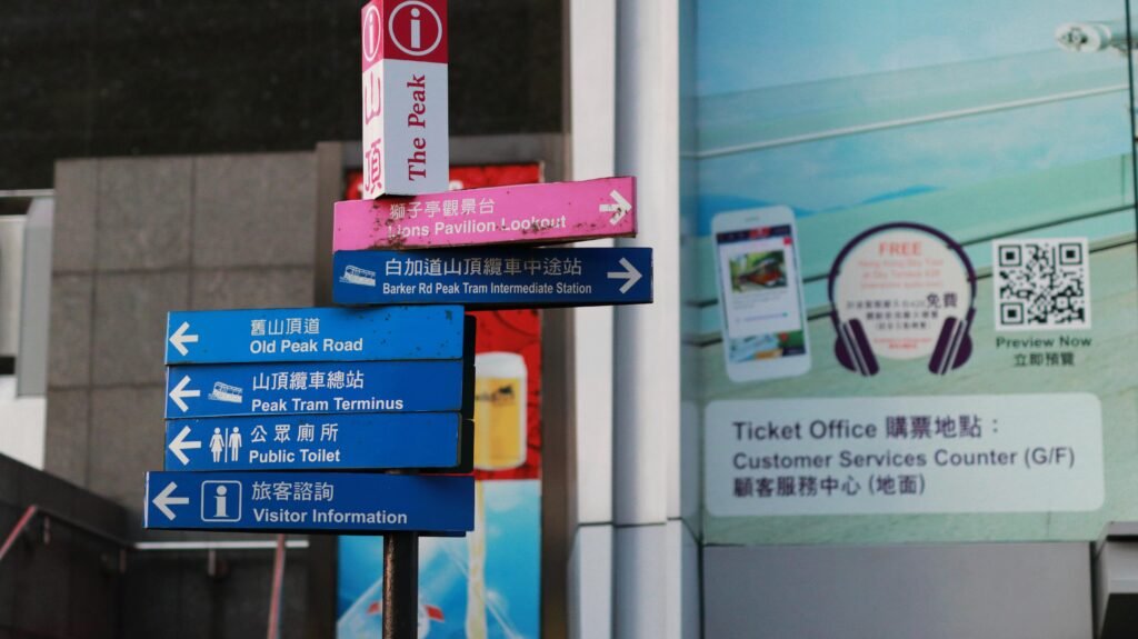 Mehrere verschiedene Schilder an einem Pfahl vor einem modernen Gebäude im Stadtgebiet