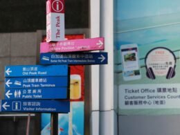 Mehrere verschiedene Schilder an einem Pfahl vor einem modernen Gebäude im Stadtgebiet